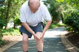 man holding knee on park path