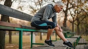 man holding knee on a park bench