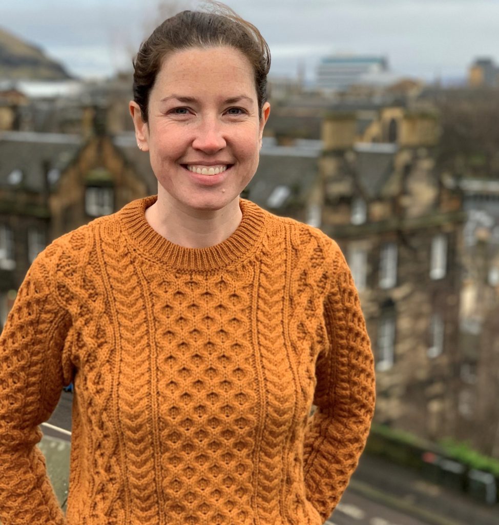 Claire Campbell white woman smiling wearing an orange jumper