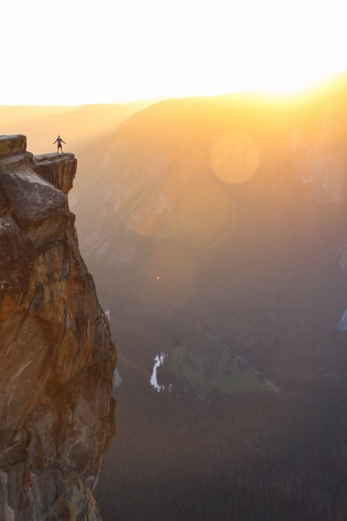 person standing on cliff looking at the view