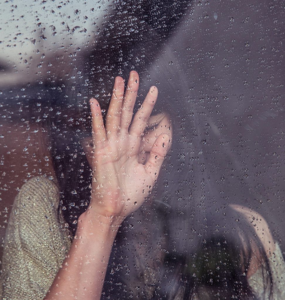 woman behind a rain splashed glass